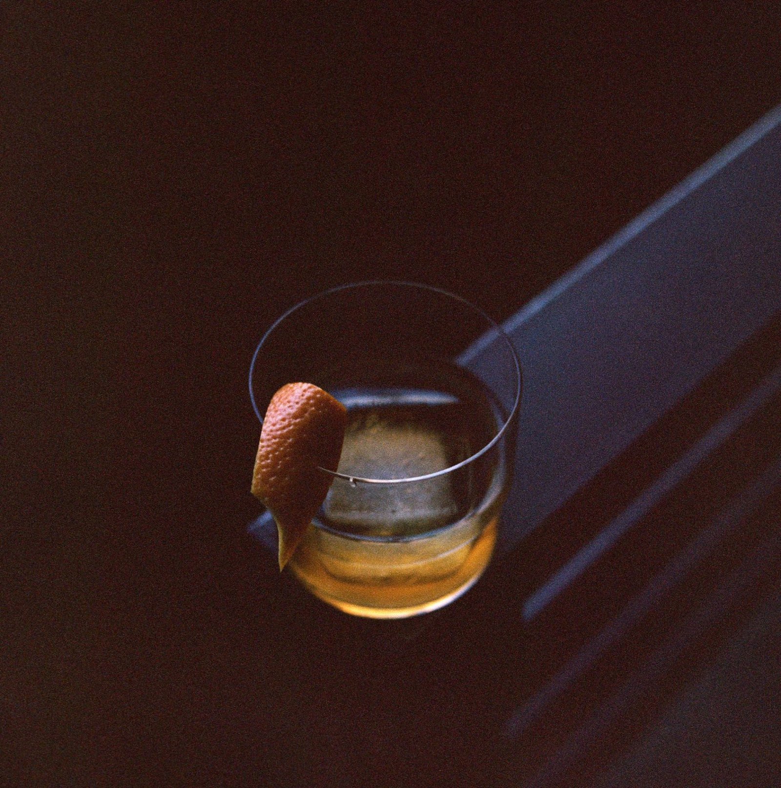 Whiskey on the rocks with an orange peel on the bar at Margolis