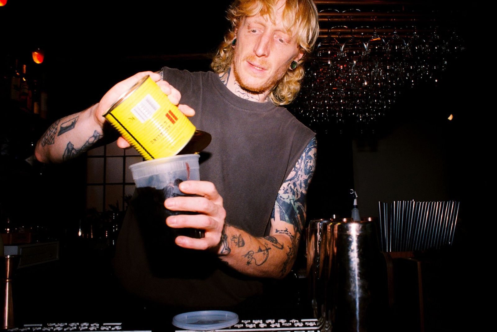 Bartender pouring cold brew from a tin into a mixing container behind the bar