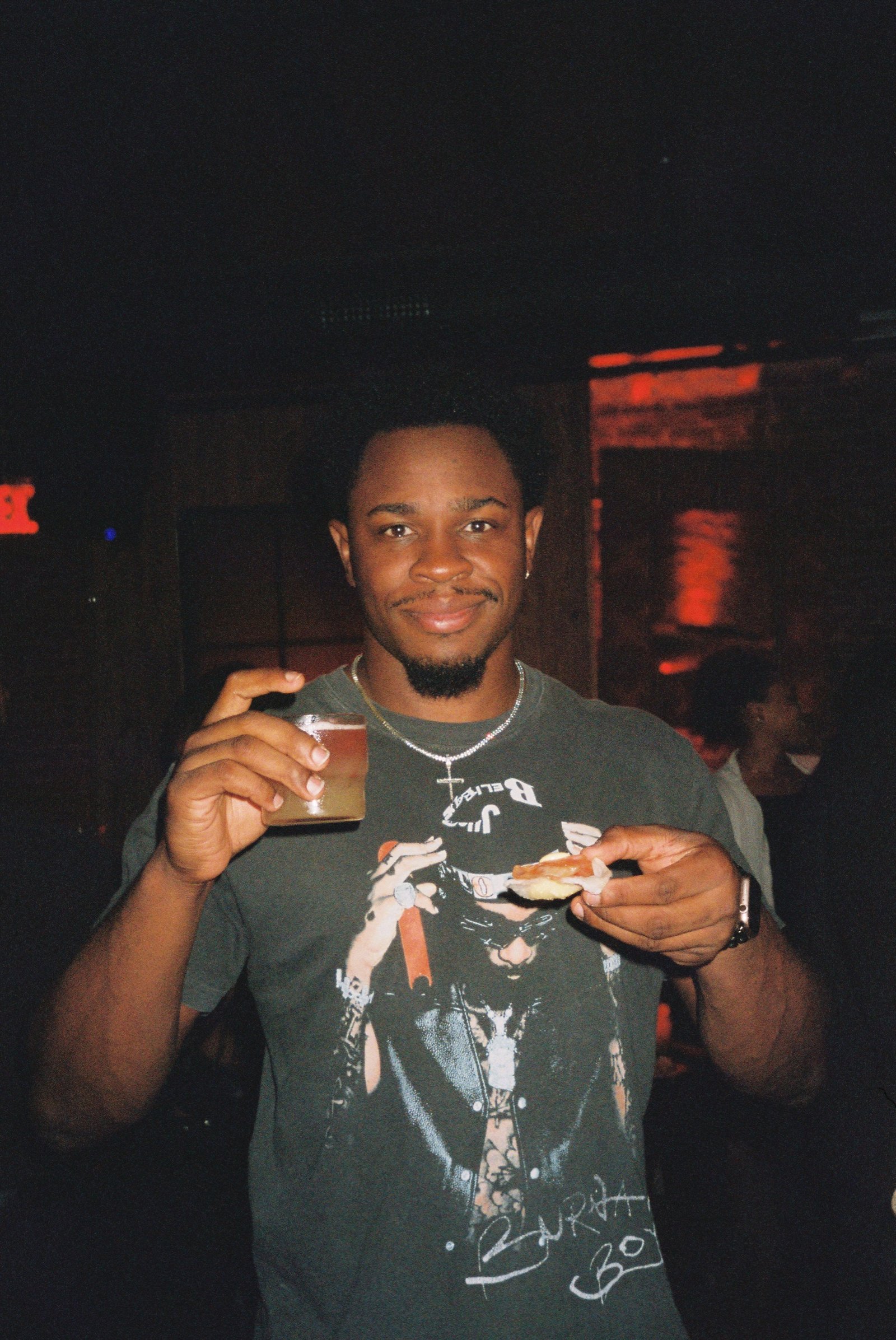 Guest holding a cocktail and a small plate of bar bites on a busy night