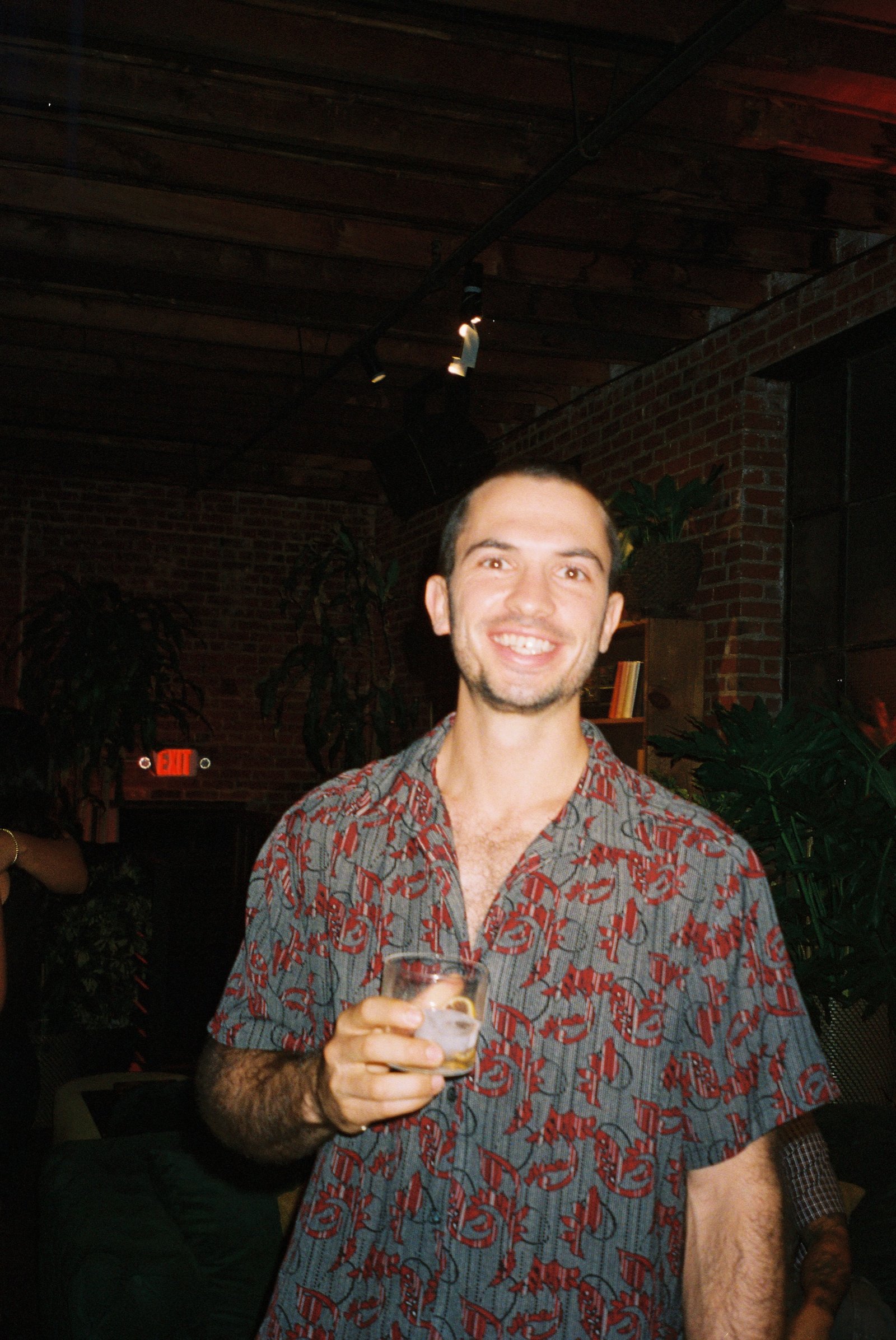 Guest in a red patterned shirt with a drink under the exposed ceiling beams