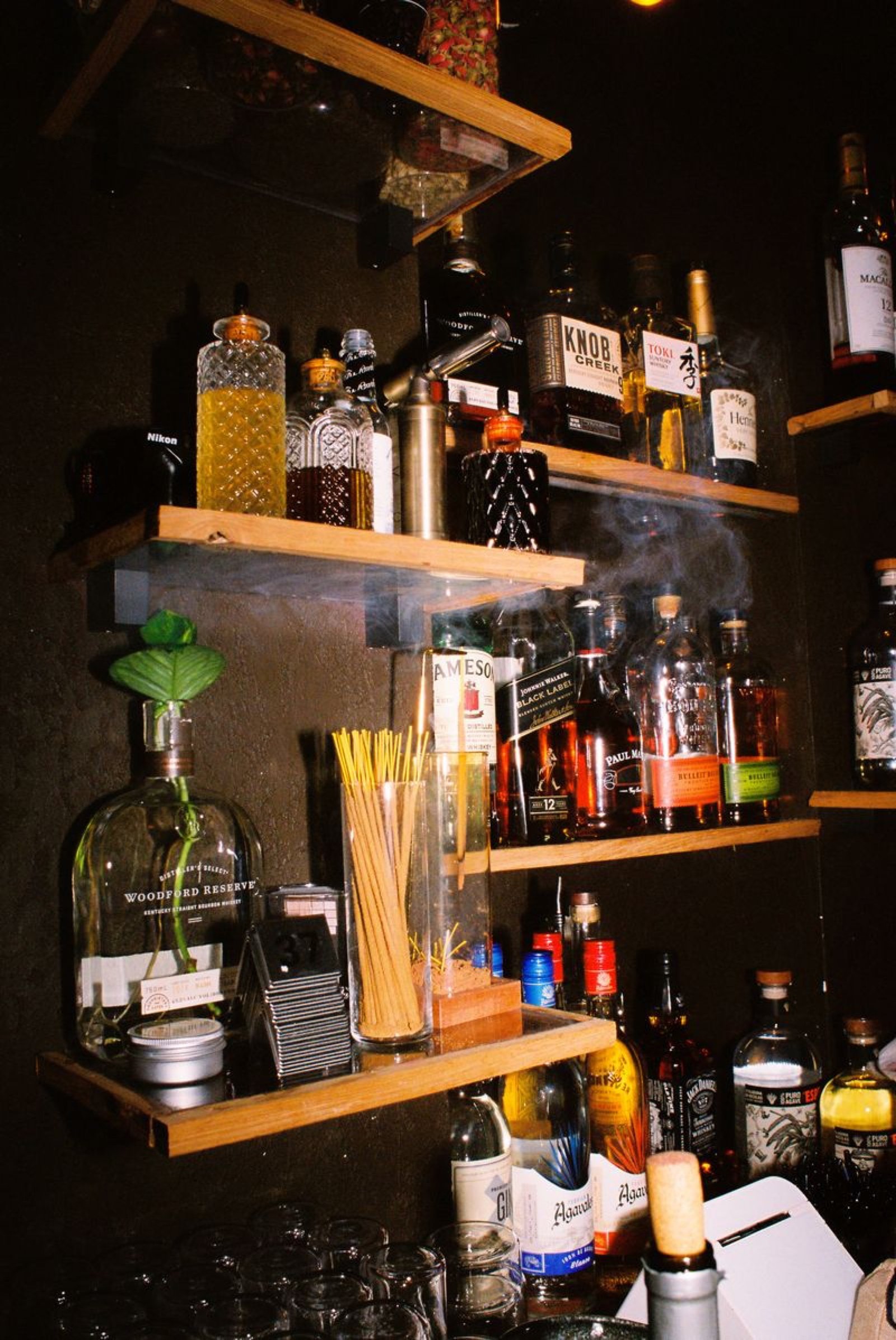Backbar shelves of whiskey, bitters, straws and bar tools at Margolis