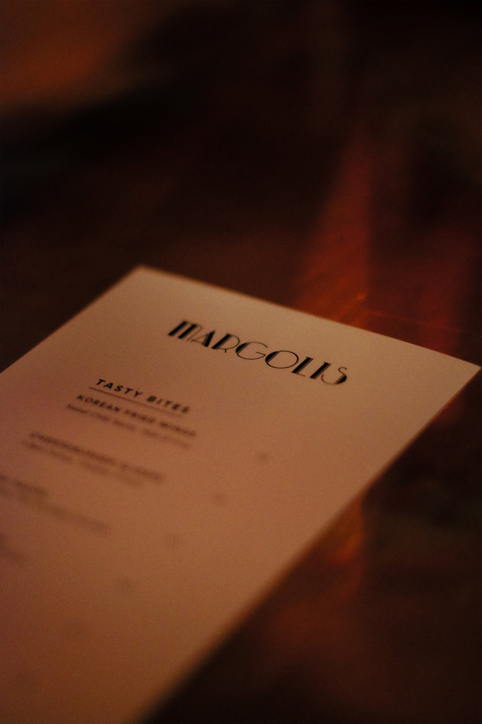 The Margolis menu card resting on a table under warm low light
