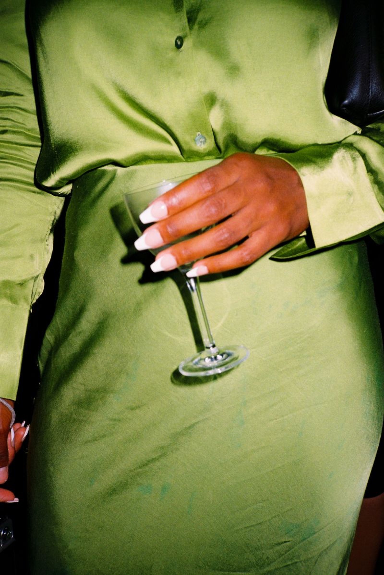 Guest in a green silk dress holding a stemmed cocktail glass