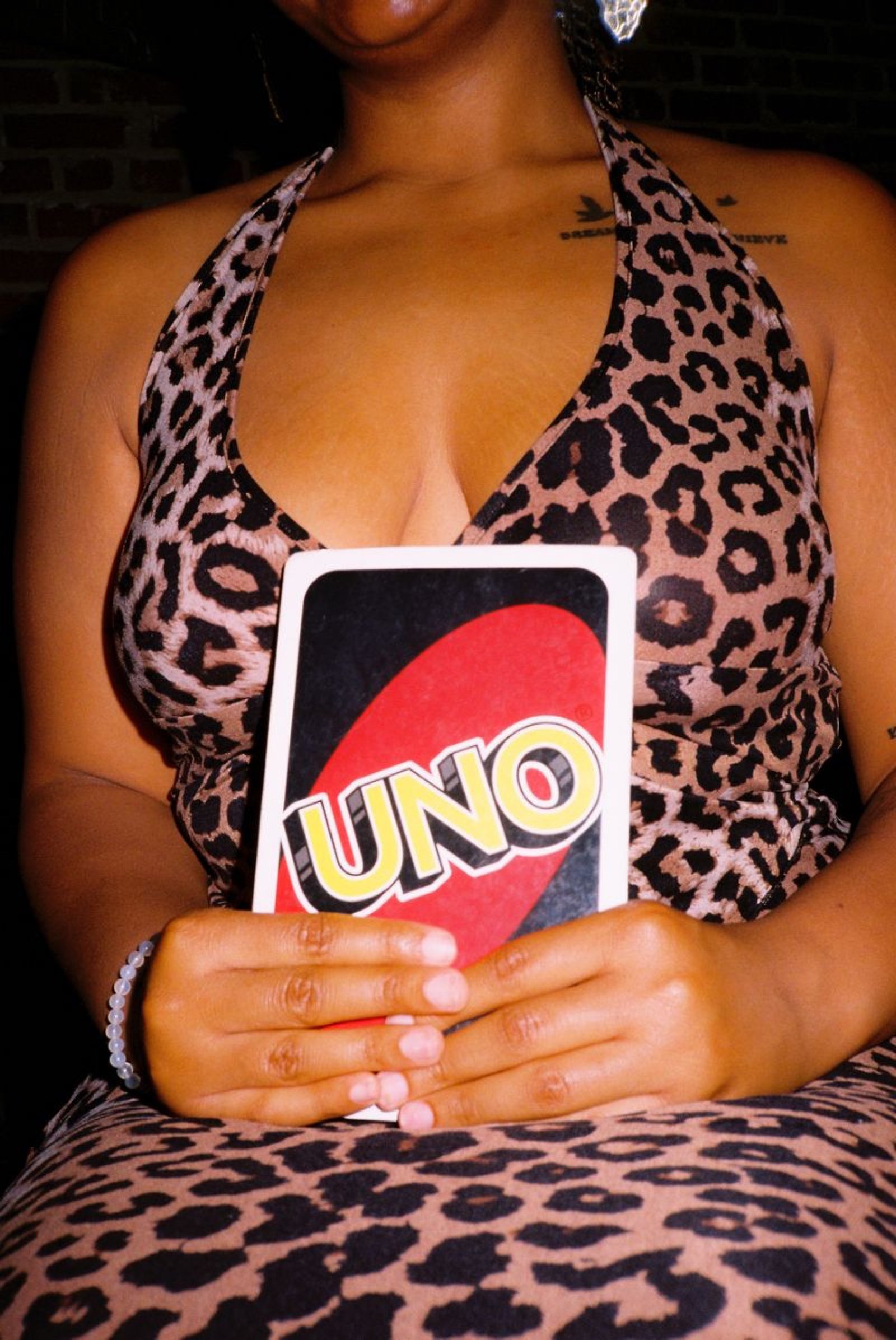 Guest in a leopard-print dress holding up an UNO card on game night