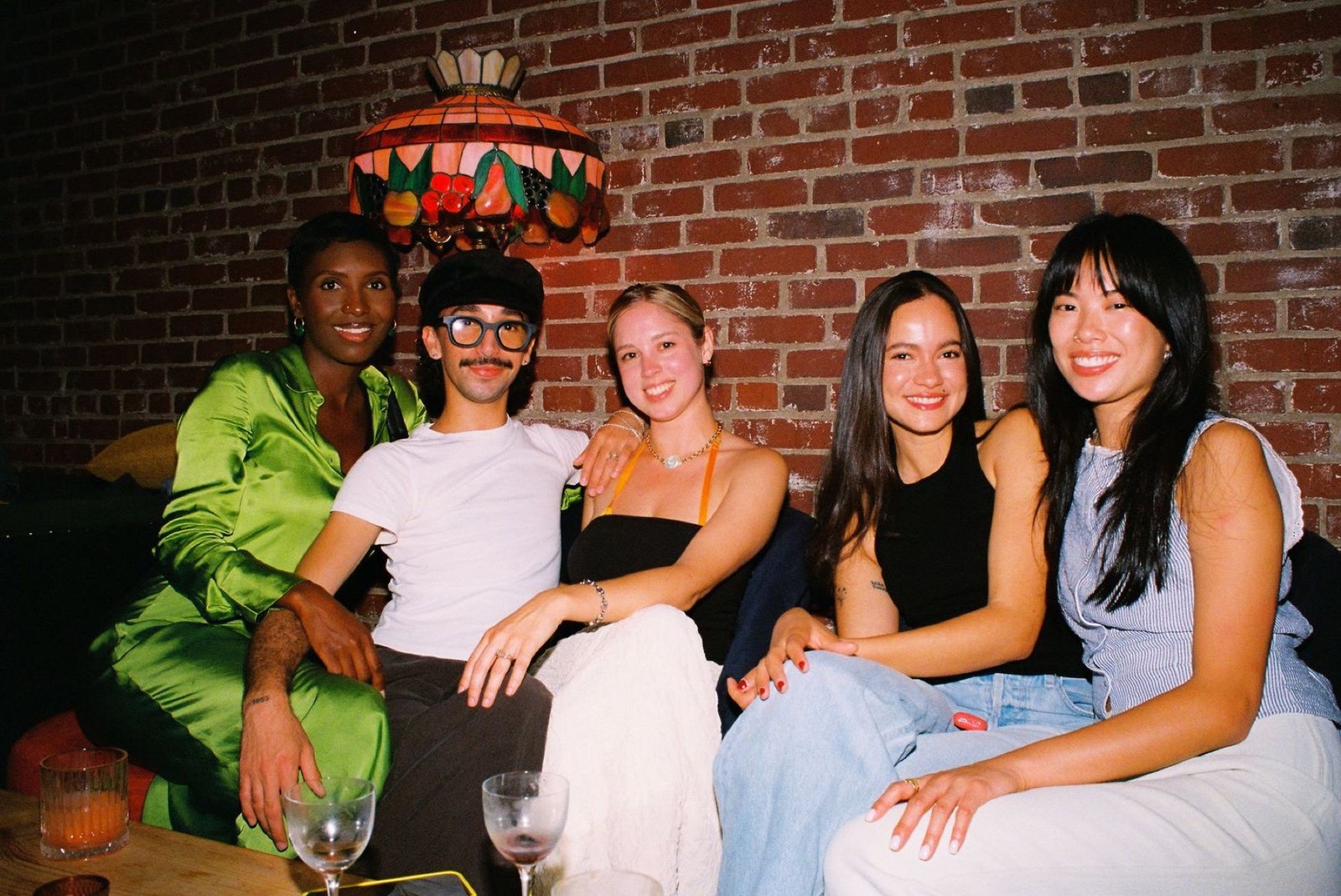 Five friends together on the sofa beneath a stained-glass pendant lamp
