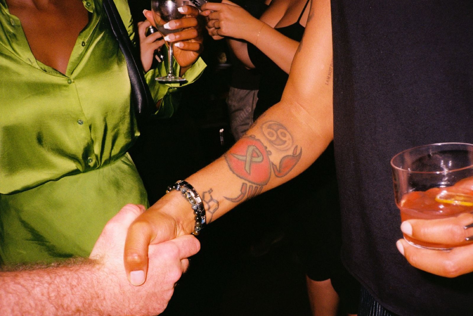 A handshake in the crowd, drinks in hand, on a busy night at Margolis