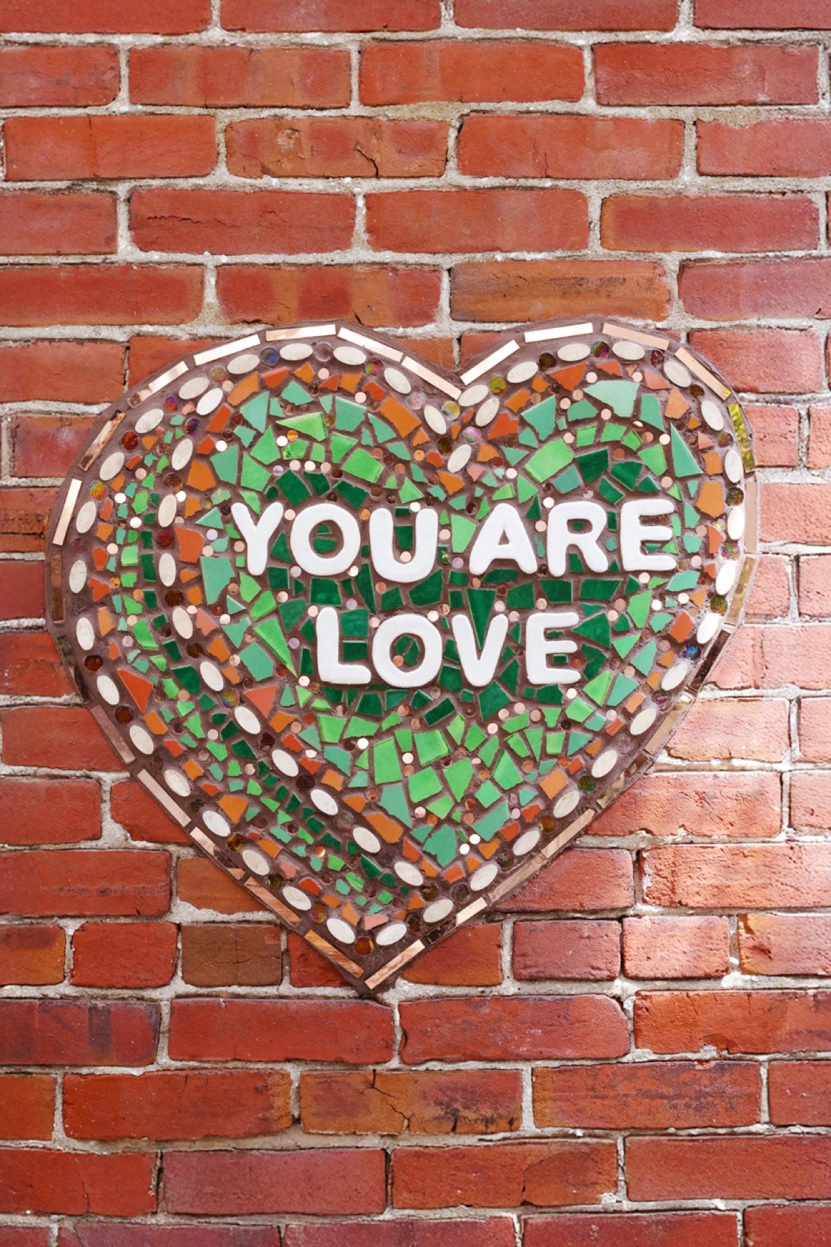 The 'You Are Love' mosaic heart close up on The Patio's brick wall