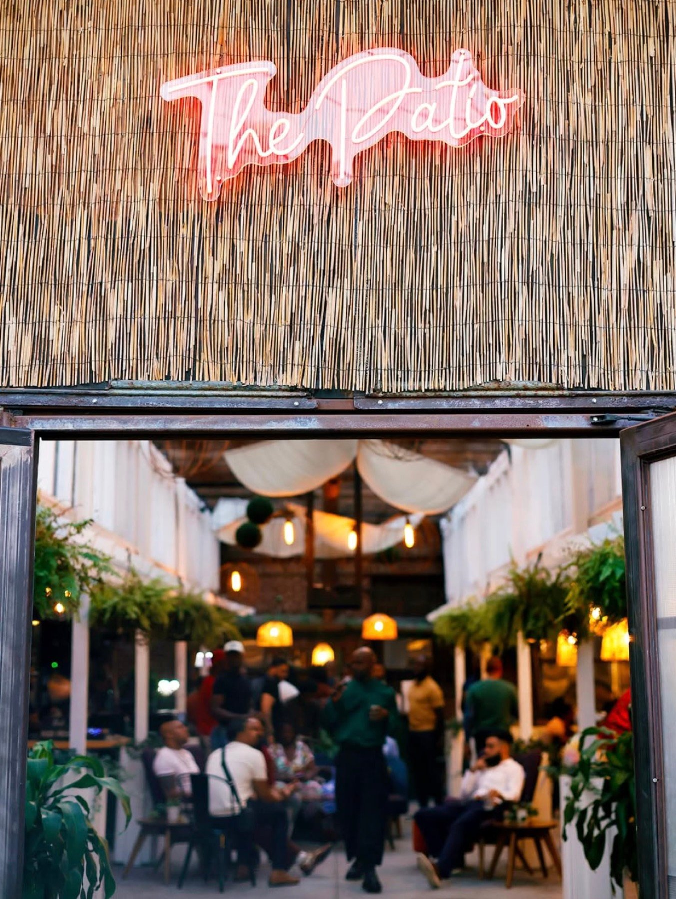 Pink neon 'The Patio' sign above the entrance to the open-air room